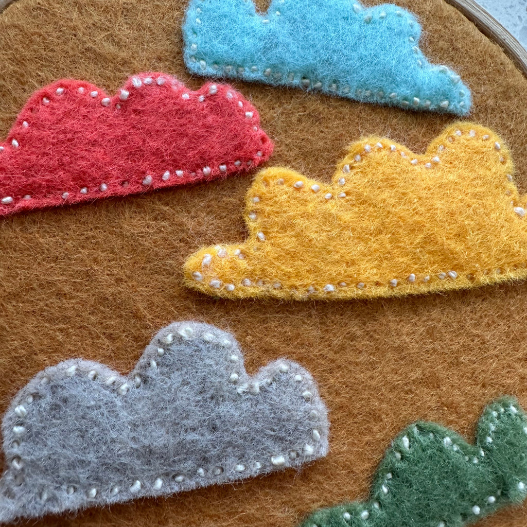 Felt cloud embroidery on hoop, burnt yellow/orange
