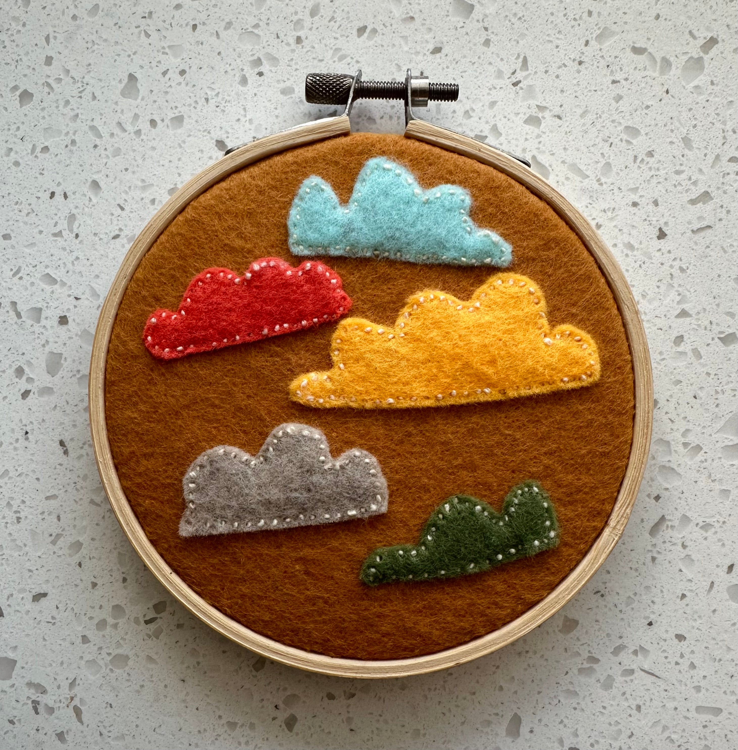 Felt cloud embroidery on hoop, burnt yellow/orange